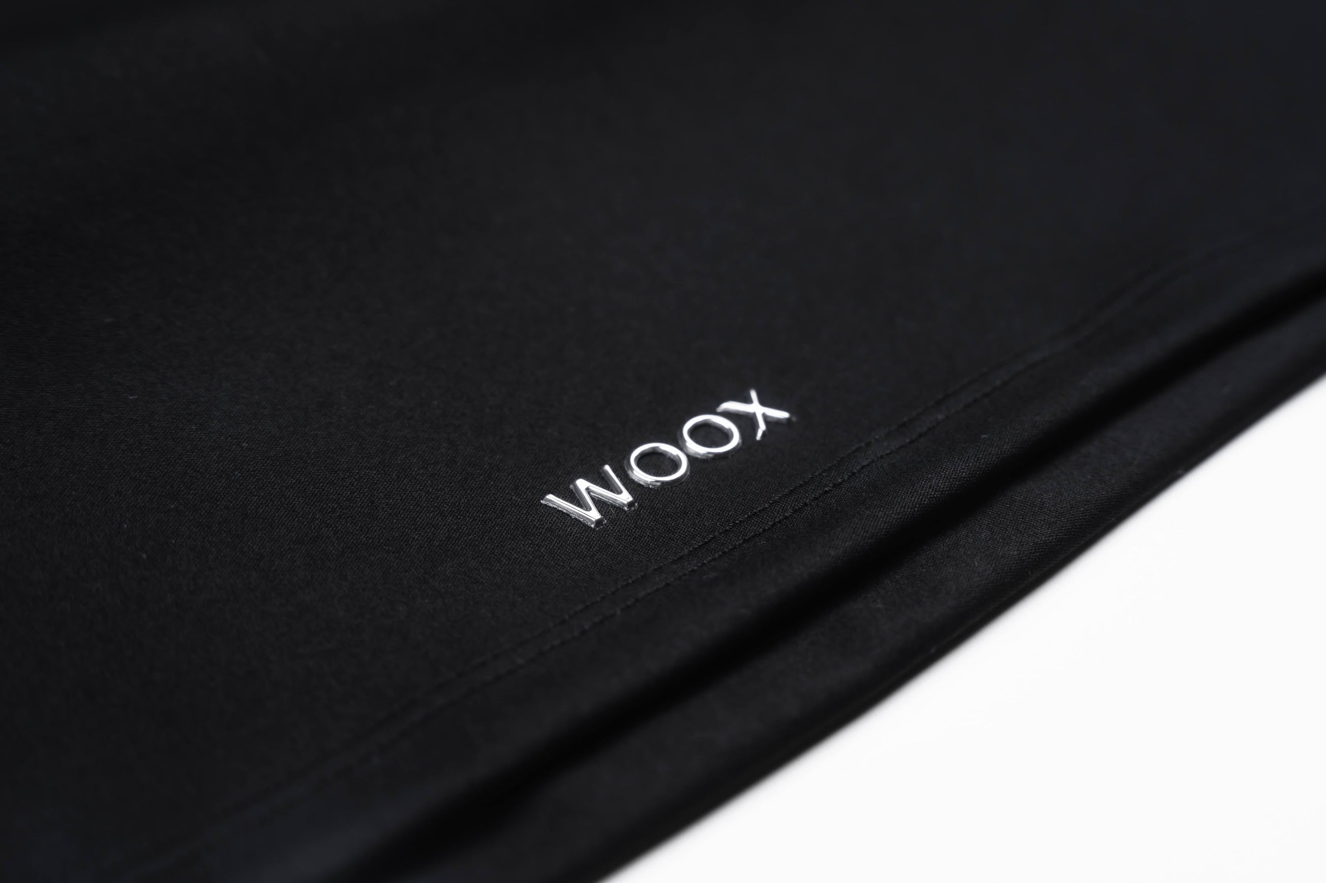 Close-up of a black surface with 'WOOX' branding.